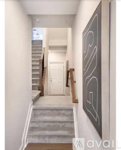 A hallway with a staircase and a painting on the wall.