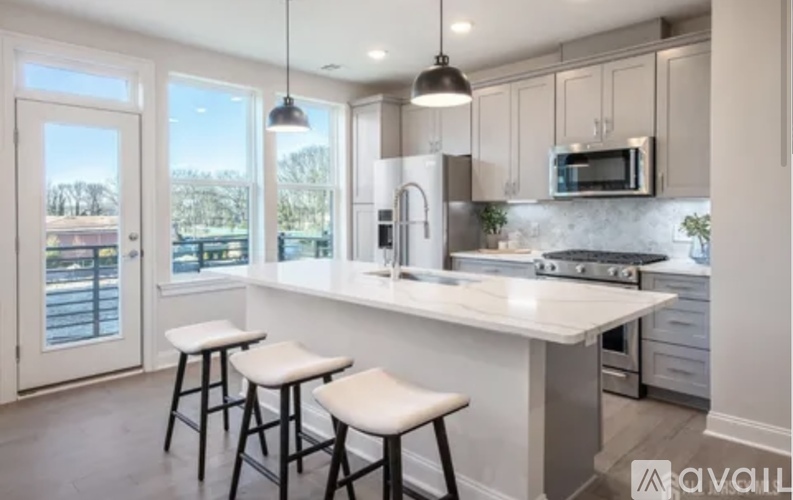 A kitchen with white countertops and a window overlooking a deck.