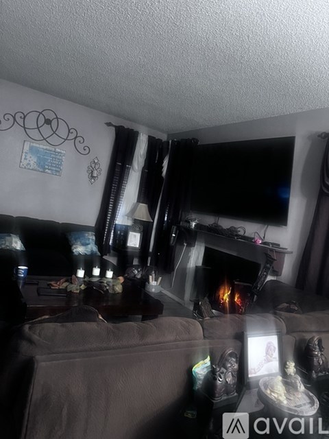 A living room with a grey couch and a fireplace.
