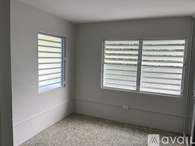 A room with a window covered by white blinds.