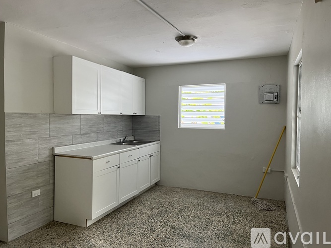 A kitchen with white cabinets and a grey countertop.