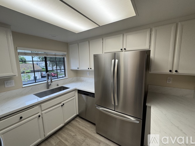 A kitchen with a stainless steel refrigerator and white cabinets.