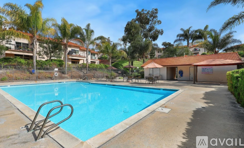 A pool with a diving board and a house in the background.