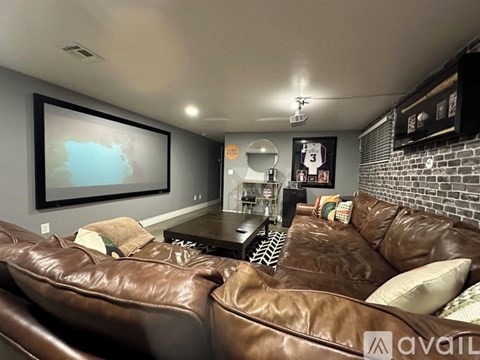 A living room with brown leather couches and a brick wall.