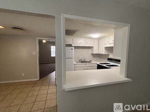 A kitchen with white cabinets and appliances is visible through a window.