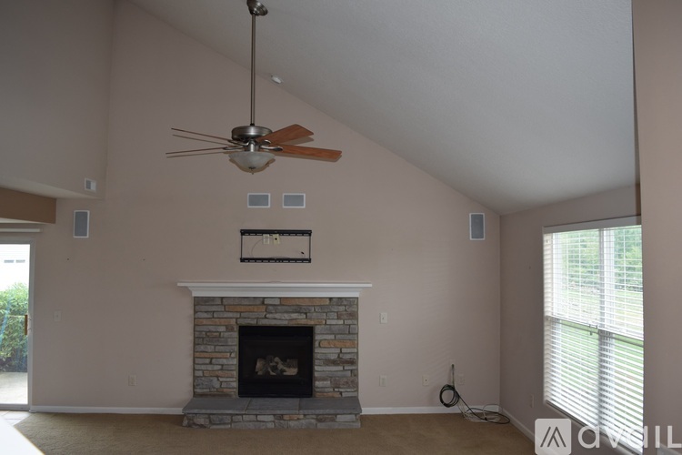 A living room with a fireplace and a ceiling fan.
