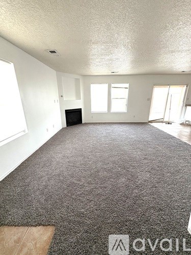 A living room with a grey carpet and a fireplace.