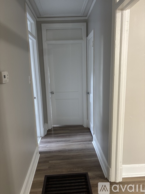 A hallway with a mat on the floor and a door at the end.