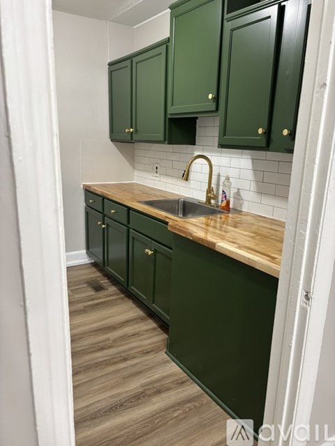 A kitchen with green cabinets and a wooden counter.