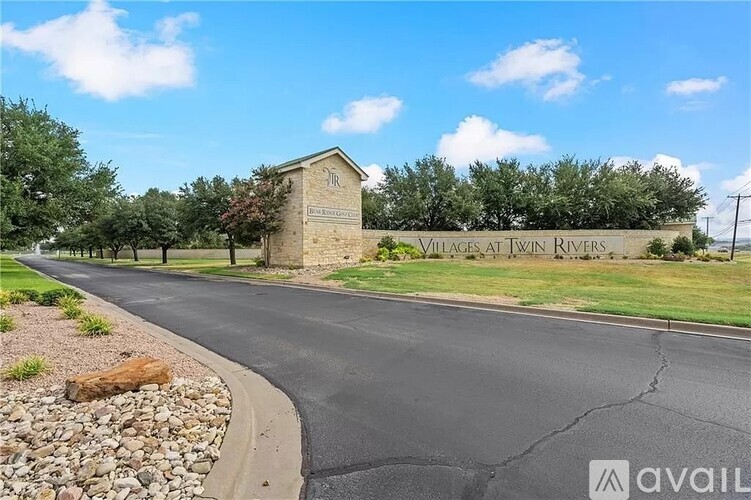 A road leads to a stone building with a sign that says Villages at Twin Rivers.