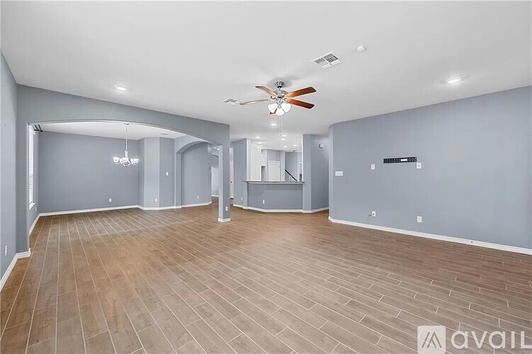 A spacious room with a ceiling fan and wooden flooring.