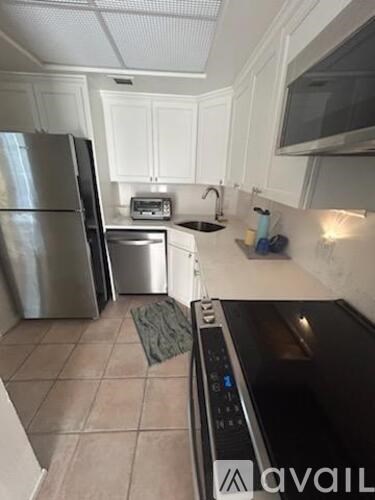 A kitchen with white cabinets and a stainless steel refrigerator.