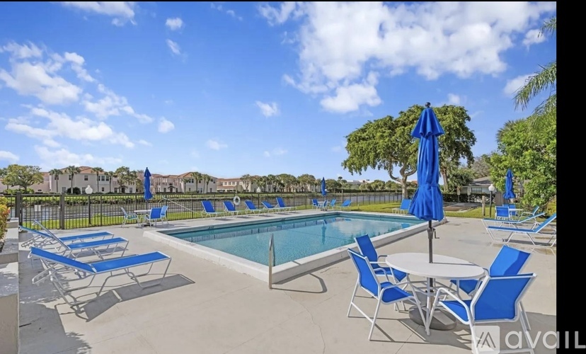 A pool area with blue chairs and umbrellas.