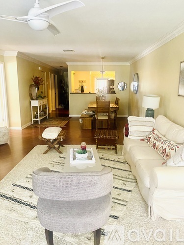A living room with a grey chair in the foreground and a white couch in the background.