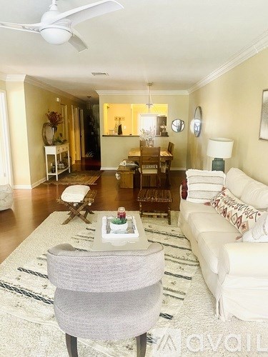 A living room with a grey chair in the foreground and a white couch in the background.