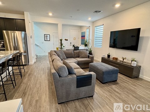 A modern living room with a grey sofa and a television on the wall.