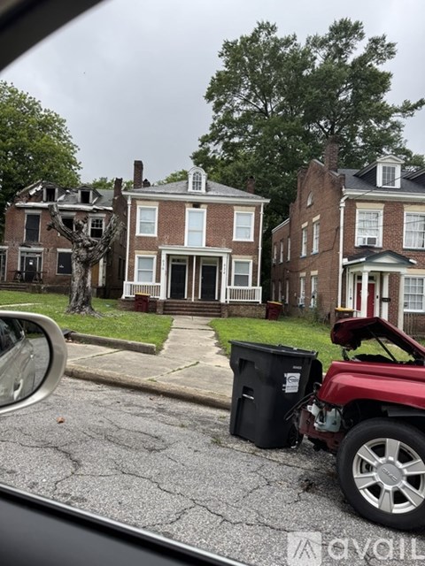 A car is parked on a street with a red vehicle in front of it.