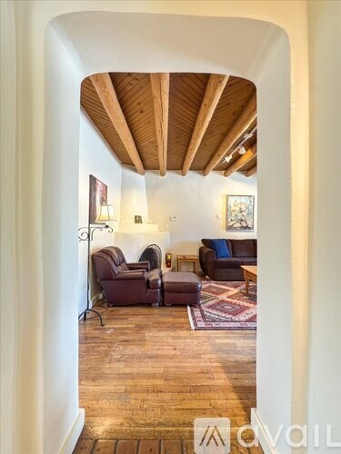 A living room with a couch, chairs and a rug.