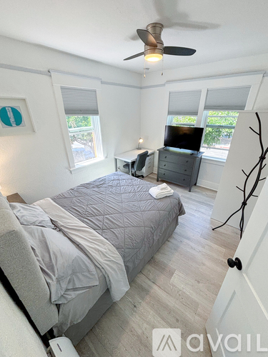 A bedroom with a bed, dresser, and ceiling fan.