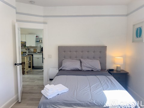 A bedroom with a large bed and a lamp on the nightstand.