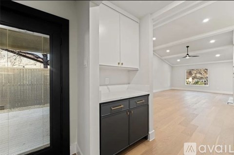 A modern kitchen with white cabinets and a black fridge.