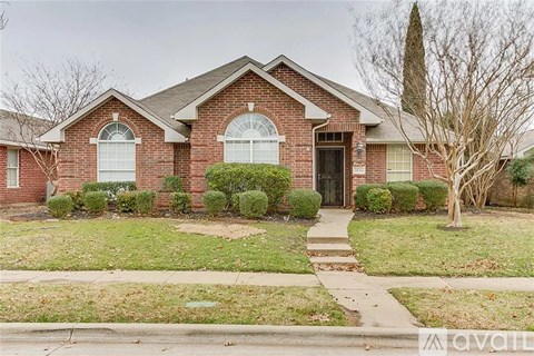 A brick house with a black door and a small front yard.