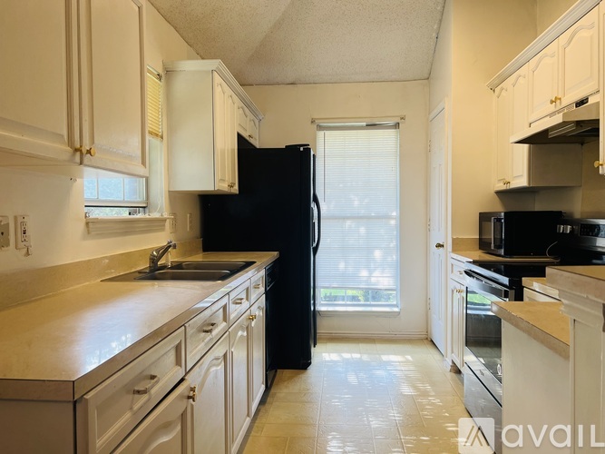 A kitchen with black appliances and white cabinets.