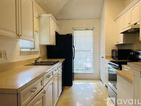 A kitchen with black appliances and white cabinets.