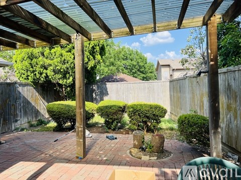A patio with a wooden pergola and a brick floor.