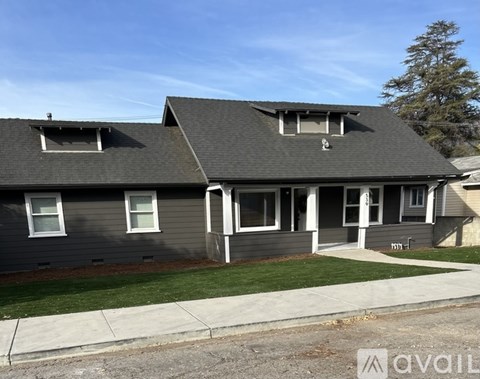 A house with a grey roof and a white window is for sale.