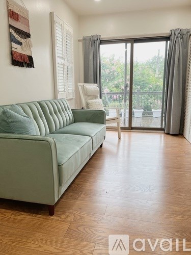 A living room with a green couch and wooden flooring.