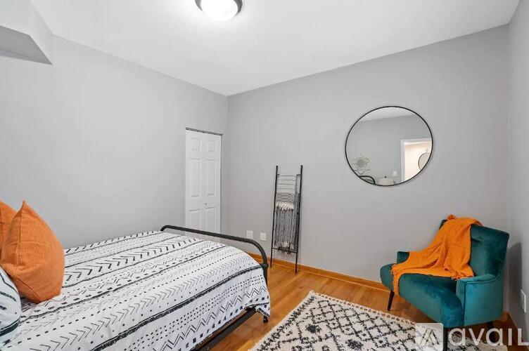 A bedroom with a bed, chair, and mirror.