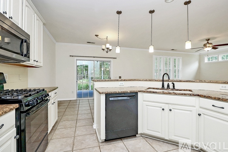 A kitchen with black appliances and white cabinets.