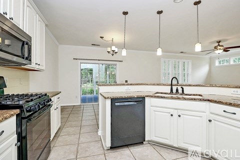 A kitchen with black appliances and white cabinets.