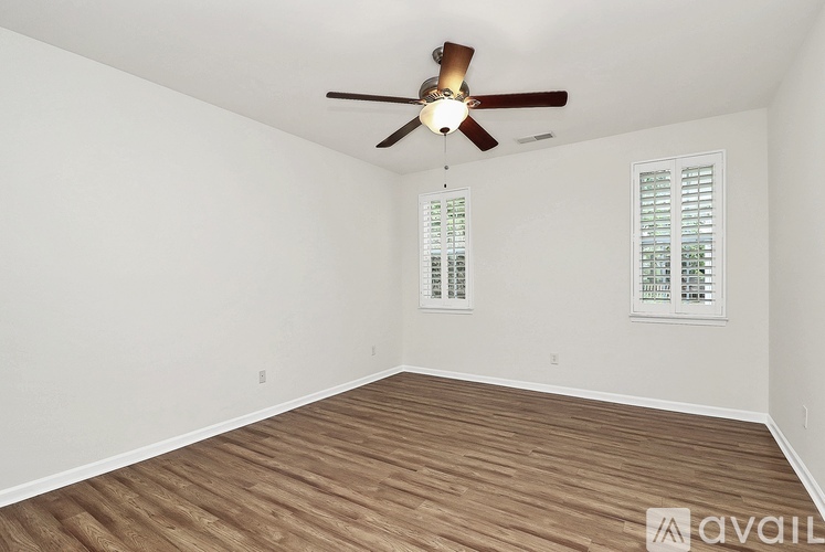 A room with a ceiling fan and wooden flooring.