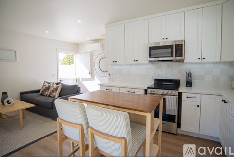 A kitchen with white cabinets and a wooden table.