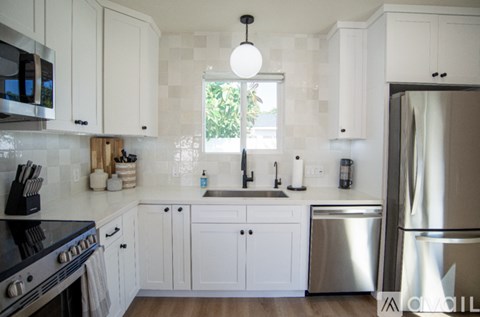 A kitchen with white cabinets and a black stove top.
