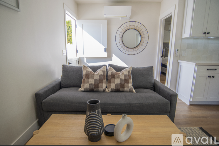 A grey couch with a round mirror above it in a living room.