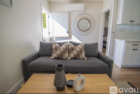 A grey couch with a round mirror above it in a living room.