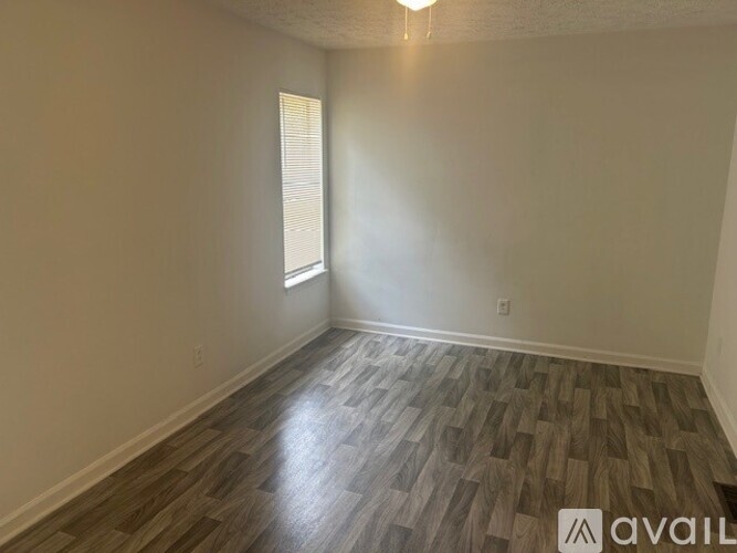 A room with wooden flooring and a window with blinds.