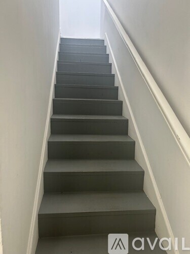 A set of stairs with a white wall on the side.