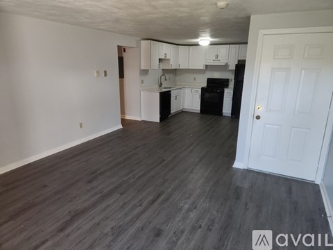 A kitchen with white cabinets and a black refrigerator.