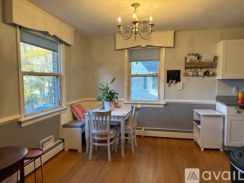 A dining room with a table set for two and a kitchen area with a stove top oven.