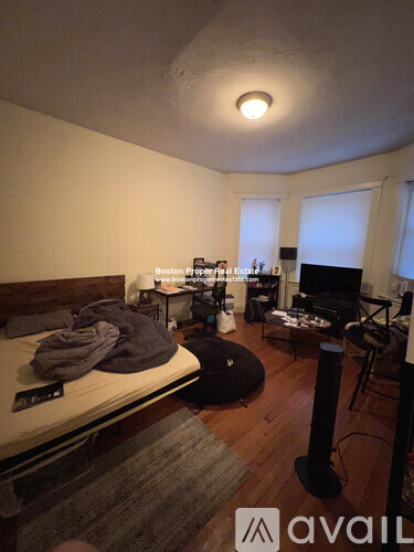 A bedroom with a bed, a desk with a chair, and a window with blinds.