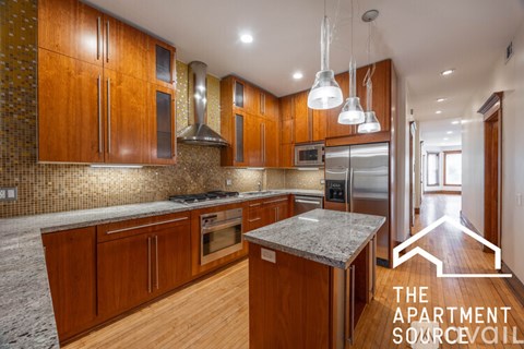 A modern kitchen with wooden cabinets and a marble island.