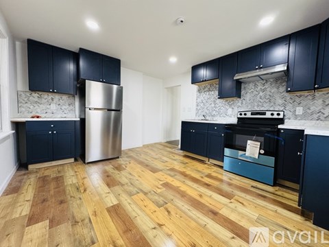 A kitchen with dark blue cabinets and a wooden floor.