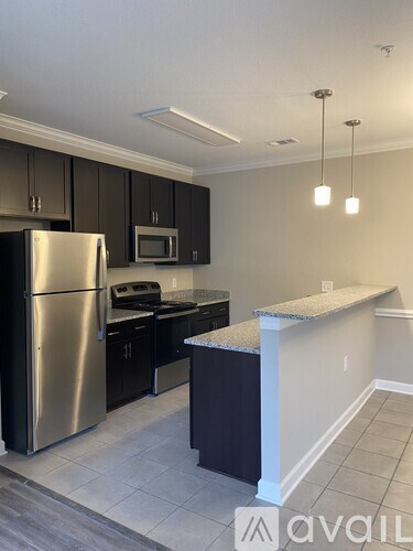 A kitchen with a stainless steel refrigerator, microwave, and black cabinets.