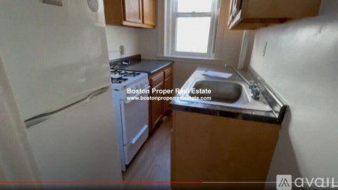 A kitchen with a white refrigerator, wooden cabinets, and a black countertop.