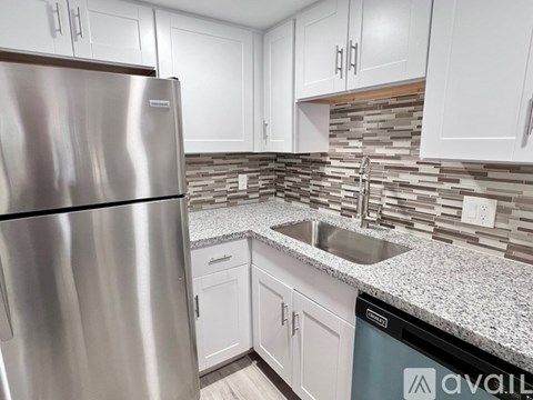 A kitchen with a stainless steel refrigerator and white cabinets.