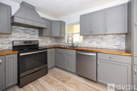 A kitchen with grey cabinets and a stone backsplash.